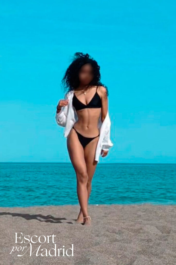 Escort mulata de lujo paseando en bikini por la playa. Alejandra